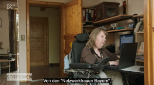 Screenshot aus der Sendung "Stationen", BR-Fernsehen, 25.5.22. Dunja Robin sitzt zu Hause am Computer. Eingeblendet ist die Untertitelung: "Von den 'Netzwerkfrauen Bayern'".