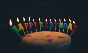 Torte mit brennenden Happy-Birthday-Buchstabenkerzen