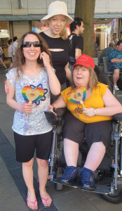 Ummahan Gräsle und Dunja Robin sind mit Assistentin Ilona auf dem Straßenfest und zeigen stolz ihre herzförmigen Regenbogenfächer